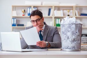 Man trying to decide whether to keep a piece of paper or throw it away